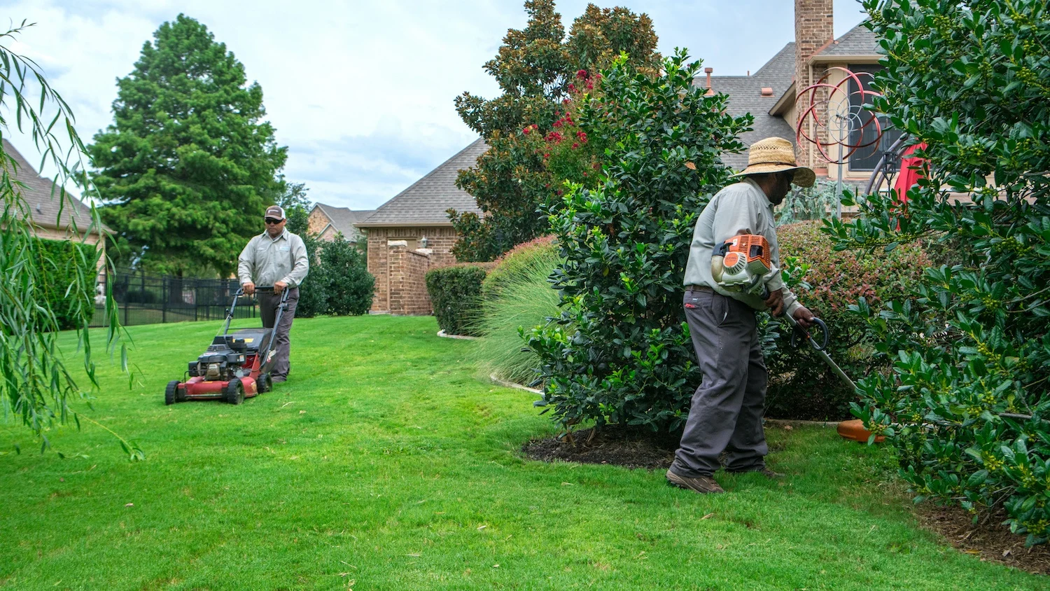 Greenscape crew mowing and trimming a residential lawn